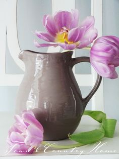 two purple flowers are in a gray vase