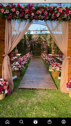 an outdoor wedding ceremony with flowers on the aisle and draping over the doorway