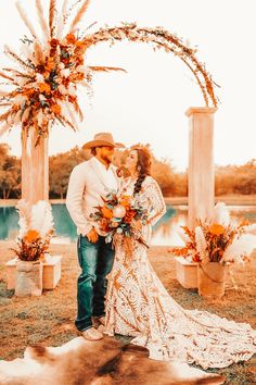 a man and woman standing under an arch with flowers