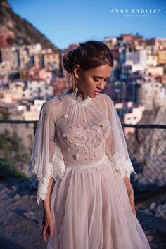 a woman in a wedding dress is standing on a balcony looking down at the city