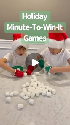 two children in santa hats are playing with marshmallows