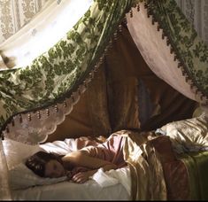 a woman laying in bed under a canopy