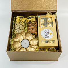 an open box containing nuts, cookies and a candle with a gold ribbon around it