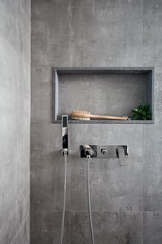 a shower head and hand held shower faucet in a bathroom with concrete walls