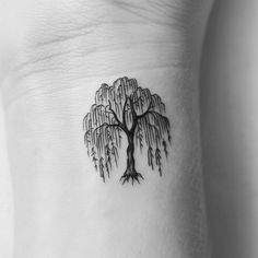 a tree tattoo on the side of a woman's left arm, with water droplets hanging from it