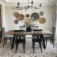 a dining room table and chairs with plates on the wall behind it, in front of a chandelier