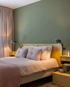 a bed with white sheets and pillows in a bedroom next to a large glass window