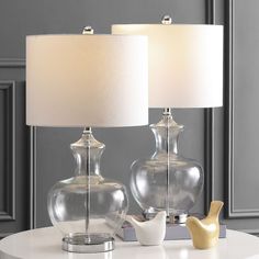 two clear glass lamps on a white table