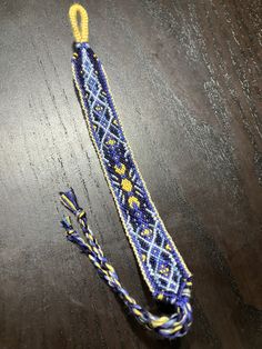 a blue and yellow beaded lanyard on a wooden table