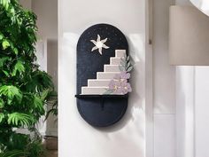 there is a cake on the wall with flowers and stars above it, next to a potted plant