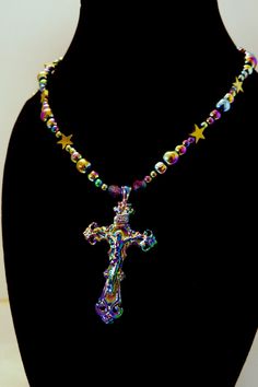 This item is an original design by me Reflecting all the colors of the rainbow, this necklace features electroplated round glass beads and an ornate metal crucifix. Star-shaped beads are gold-colored synthetic hematite. Two of the beads nearest the crucifix are Czech glass. Semi-flexible base is beading wire. Lobster clasp and jump rings are gold plated.  Please see images for scale, etc. Necklace is approximately 23" long with a 2" extender. Cross is approximately 2" in height. Total 1.2 oz/34 g in weight. Please see my shop for more religious jewelry, rosaries, animal sculptures, and more! Thank you! Spiritual Iridescent Jewelry With 8mm Beads, Spiritual Beaded Cross Pendant Jewelry, Gold Jewelry With 8mm Beads For Festivals, Spiritual Iridescent Jewelry For Festival, Spiritual Multicolor Cross Necklace, Iridescent Nickel-free Spiritual Necklaces, Multicolor Beaded Cross Jewelry, Gold Spiritual Beaded Necklace Nickel Free, Nickel-free Gold Beaded Necklace For Spiritual Wear