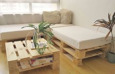 a couch made out of wooden pallets with a plant on the end table in front of it