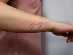 a woman's arm with a small tattoo of a dog on the left side of her arm