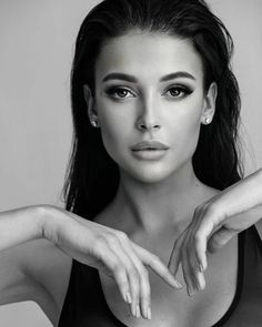 a black and white photo of a woman with her hands on her chest, looking at the camera