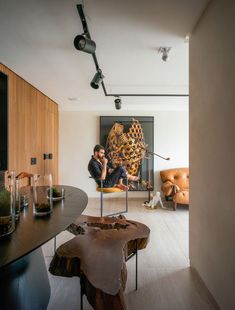 a man sitting on a chair in front of a fireplace next to a wooden table