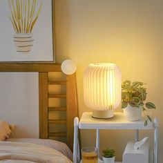 a white lamp sitting on top of a table next to a bed