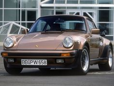 a brown porsche parked in front of a building