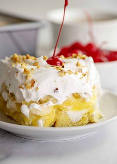 a piece of cake on a white plate with whipped cream and toppings in the background