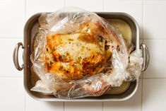 a chicken wrapped in plastic sitting on top of a pan