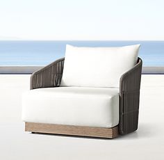 a white chair sitting on top of a cement floor next to the ocean and sky