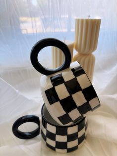 a black and white checkered container sitting on top of a table next to two candles