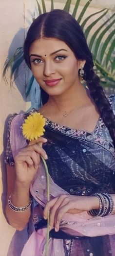 a woman holding a yellow flower in her hand