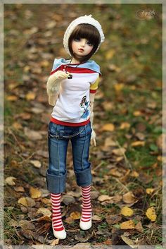 a doll is standing in the leaves wearing a hat