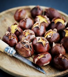 some chestnuts on a wooden plate with a knife