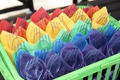 there are many colorful bags in the green basket on the table and one is filled with them