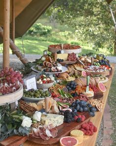 a table full of different types of cheeses and meats on display under a tent