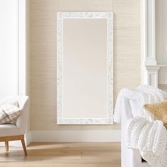 a living room with a white couch, chair and large framed mirror on the wall