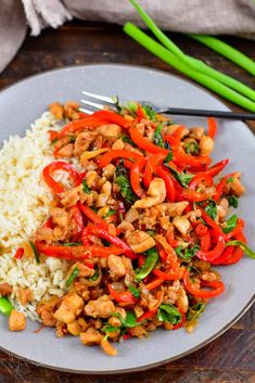 a white plate topped with rice and veggies next to chopsticks on a wooden table