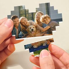 a person holding up two pieces of puzzles with pictures of people and a dog on them