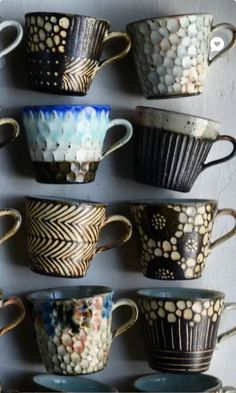 many cups are lined up on the wall and one is painted with gold leaf designs