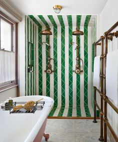 a bathroom with green and white stripes on the shower wall next to a bathtub