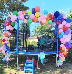 a blue trampoline covered in balloons and streamers