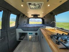 the interior of a camper van with a bed and stove top oven in it