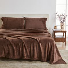 a bed covered in brown sheets and pillows