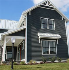 a gray house with white trim on the front and side windows is pictured in this image