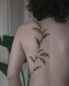 the back of a woman's upper body with leaves on her left and right side