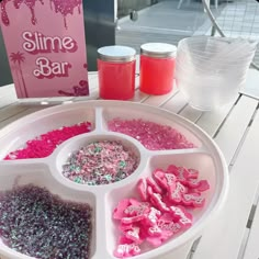 a white tray topped with lots of pink and purple sprinkles on top of a table