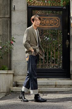 a young man walking down the street in front of a building with an iron gate