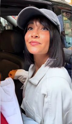 a woman sitting in the back seat of a car wearing a hat and white jacket