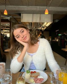 a woman sitting at a table with food and drinks