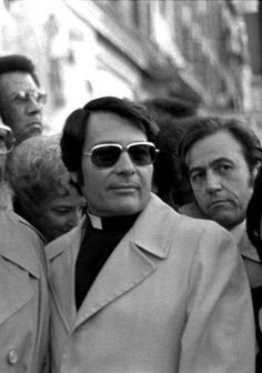 black and white photograph of people standing in front of a building with sunglasses on their faces