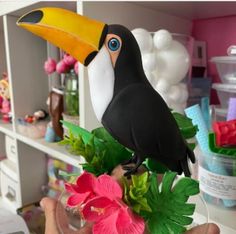 a fake toucan sitting on top of a vase filled with flowers