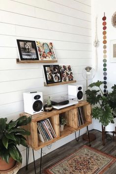 a room with some plants and pictures on the wall above it, along with an area rug