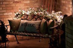 a bench with christmas lights on it in front of a brick wall and window sill