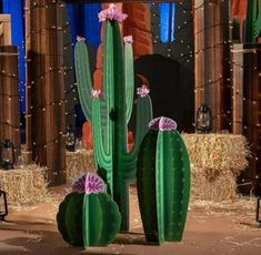 a large cactus with pink flowers in front of hay bales and lights behind it