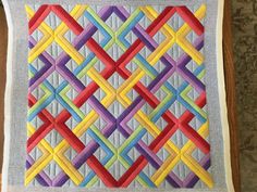 a quilted wall hanging with colorful strips on it